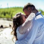 A loving embrace and kiss between a bride and groom outdoors.